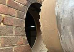 Diamond Drilling A large drill bit making a circular hole in a brick wall.