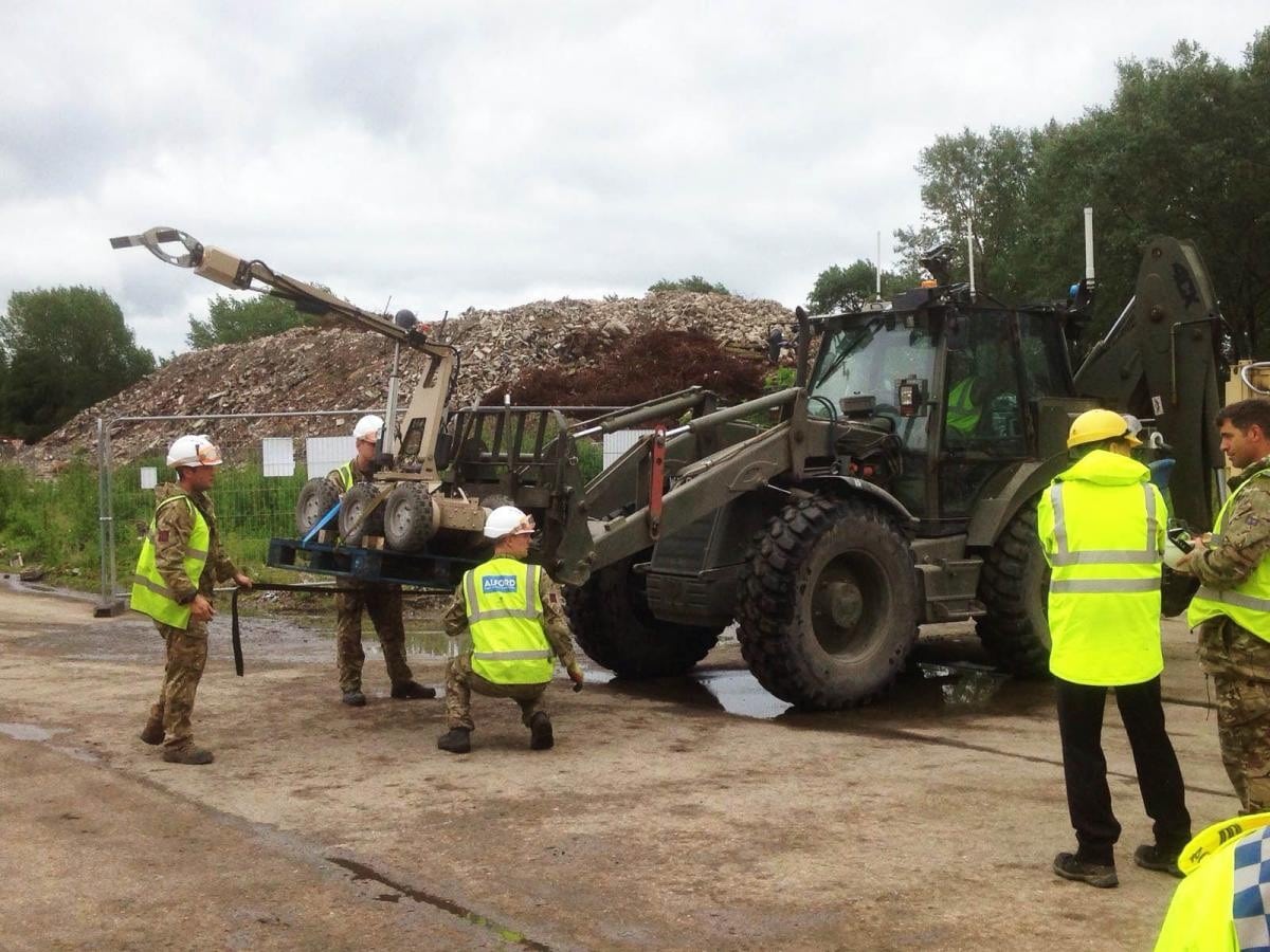Didcot - Projects Workers in safety gear operate machinery at a construction or demolition site with rubble in the background.