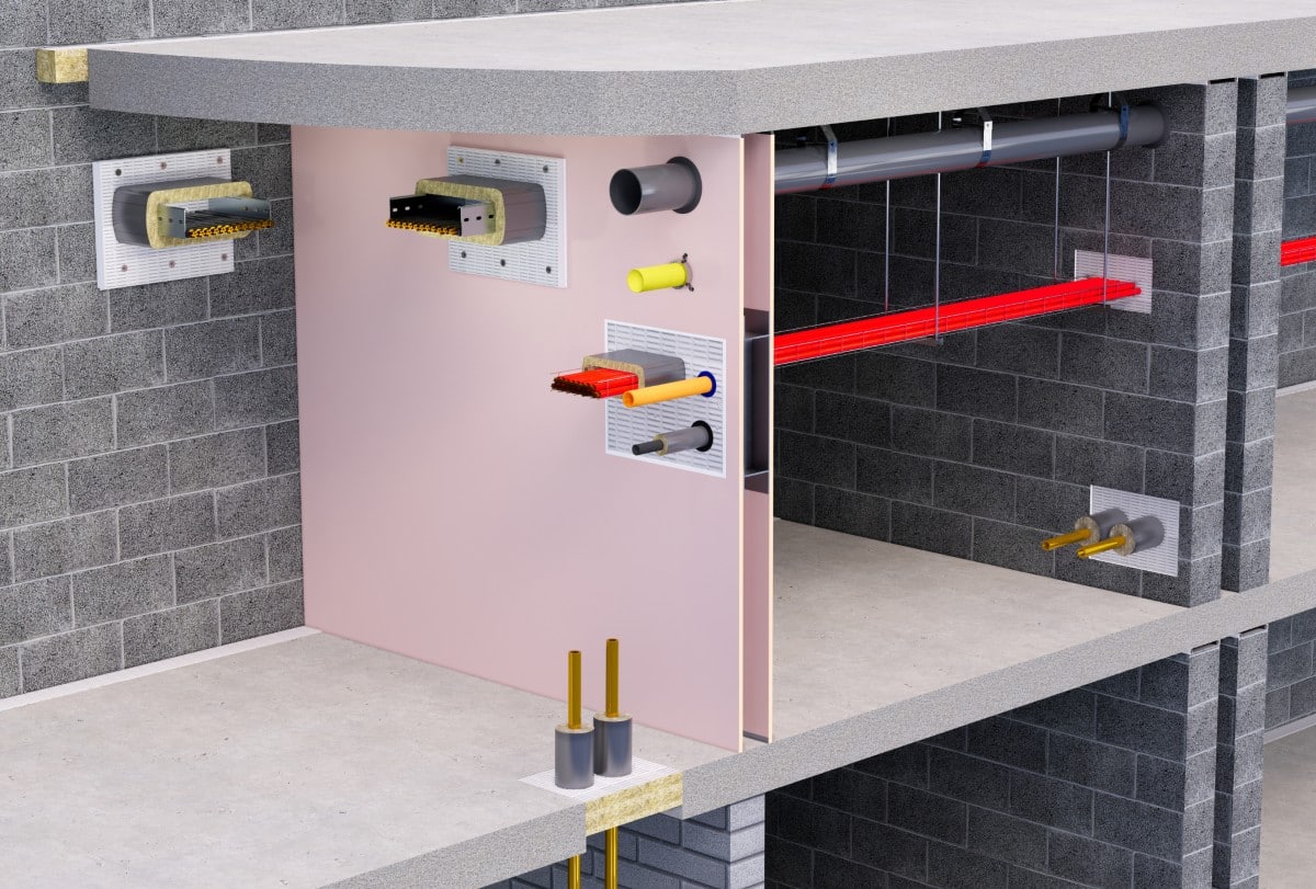 Cutaway view of fire-protected wall and floor with pipes and cables running through building structure.