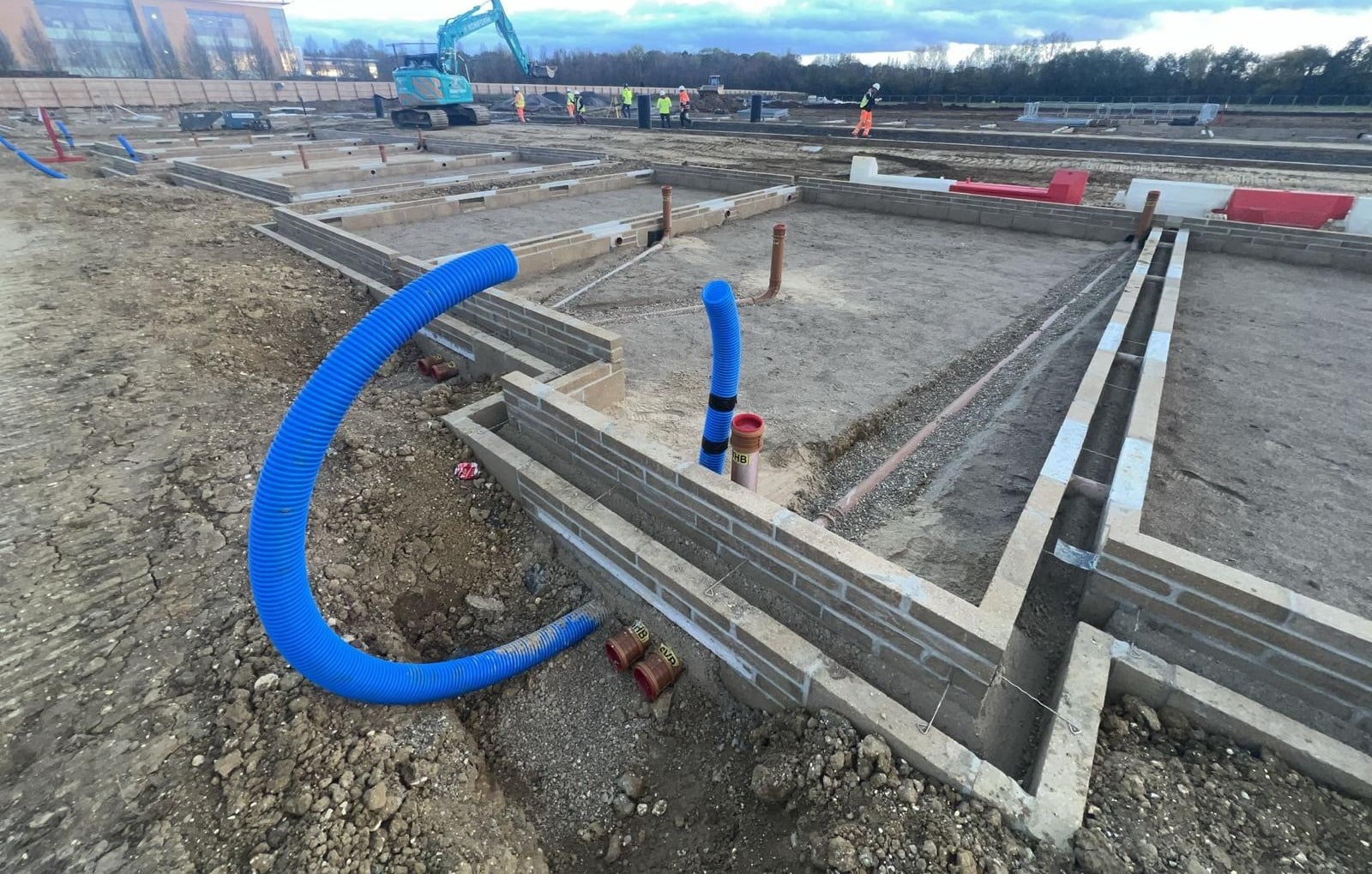 Foundations Concrete foundations with blue utility pipes at a construction site.