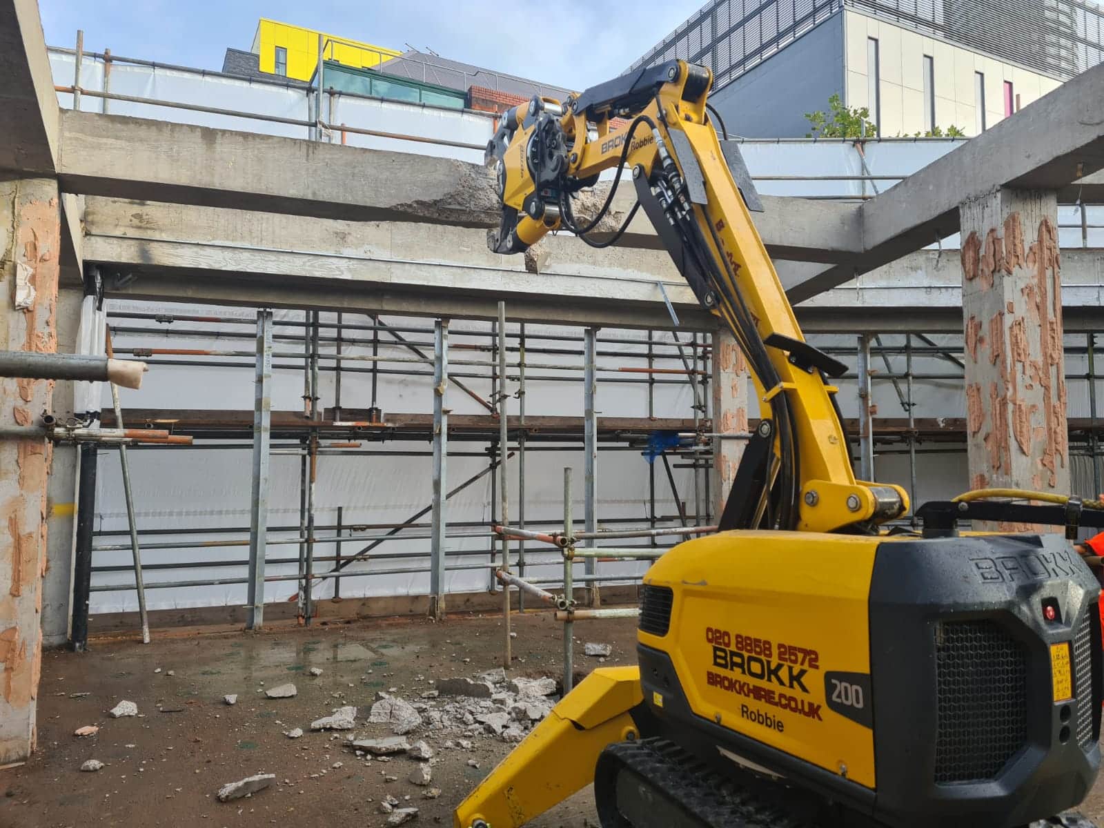 Robotic Hydraulic Crunching A yellow robotic machine crunches a concrete beam at a construction site.