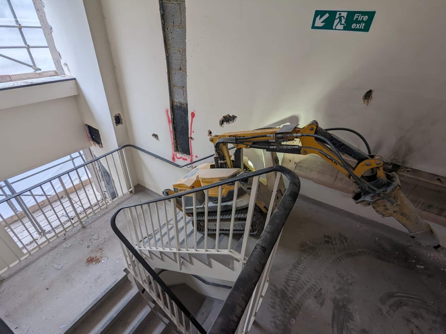Soft-Strip Demolition A demolition robot breaks through a stairwell wall in a building under renovation.