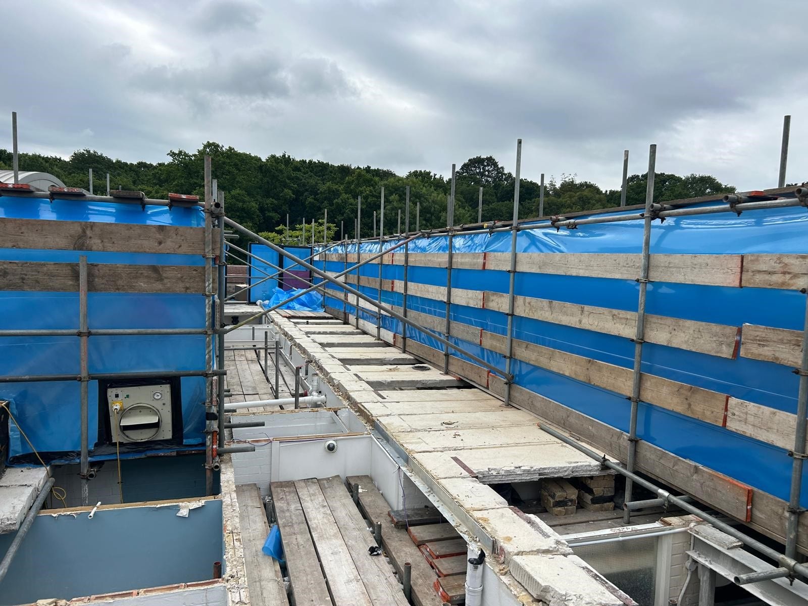 Construction site with scaffolding and temporary walkways under a cloudy sky.