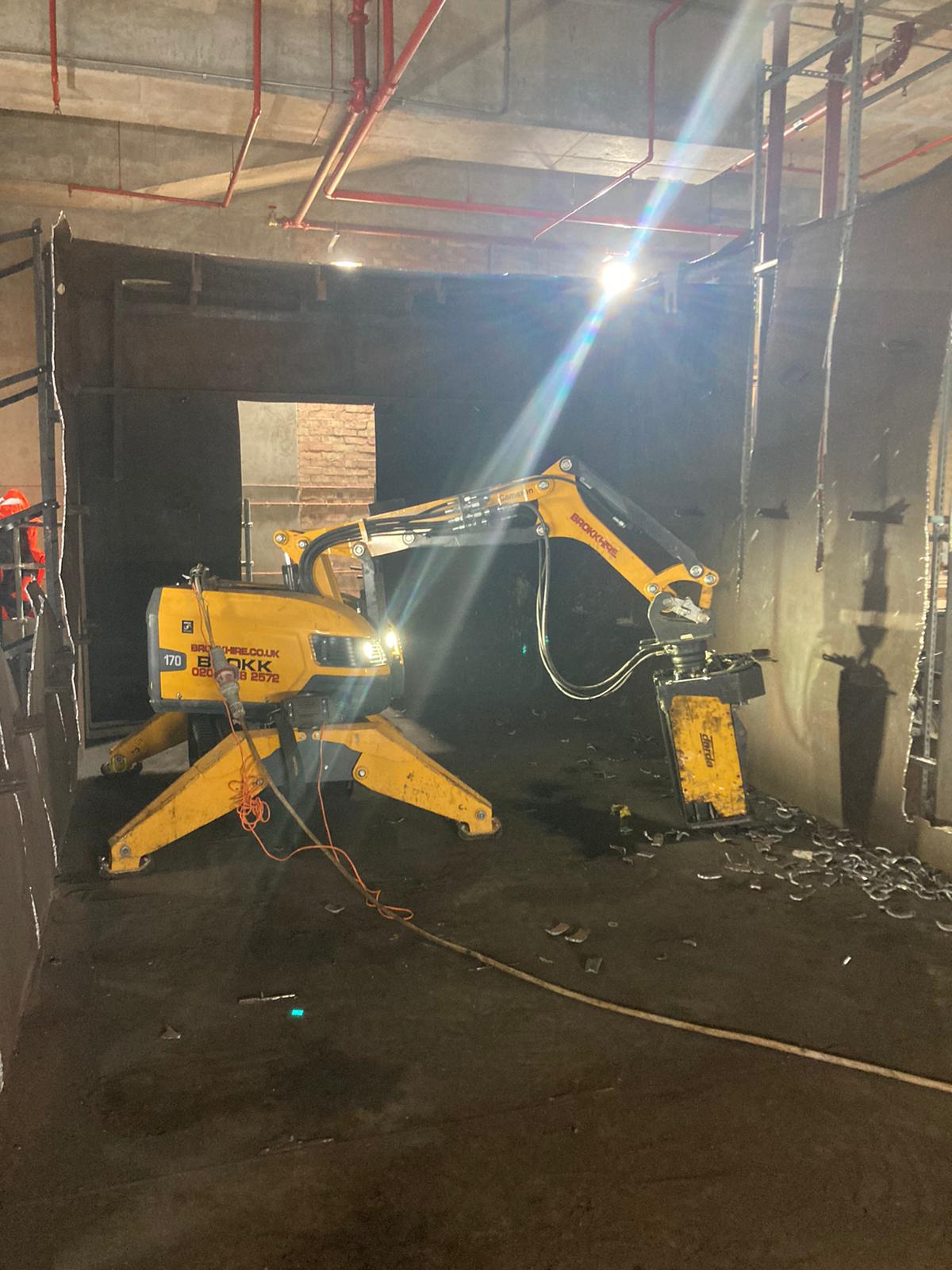 brokk170 01 A yellow demolition robot breaking concrete inside a building under construction.