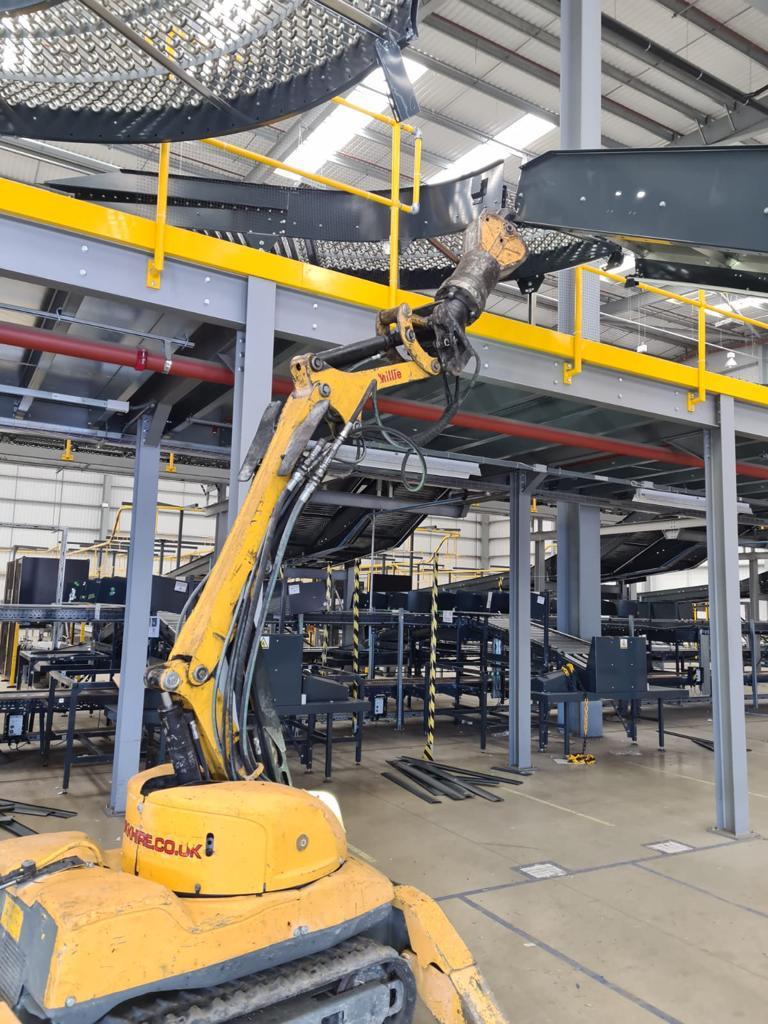 dilaps SCK01 A yellow demolition robot operates inside an industrial warehouse with metal structures.