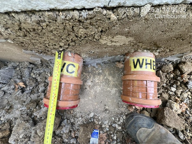 drainage3 Two labeled drainage pipes, "WC" and "WHB," in soil with a measuring tape beside them.