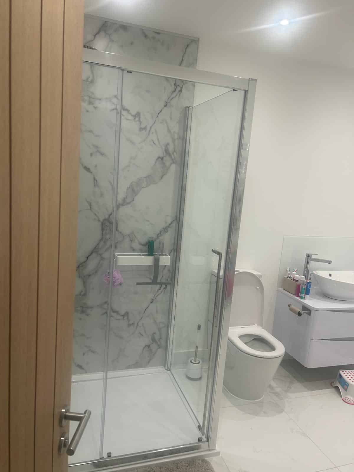 Modern bathroom with a glass shower, toilet, and sink with cabinet.