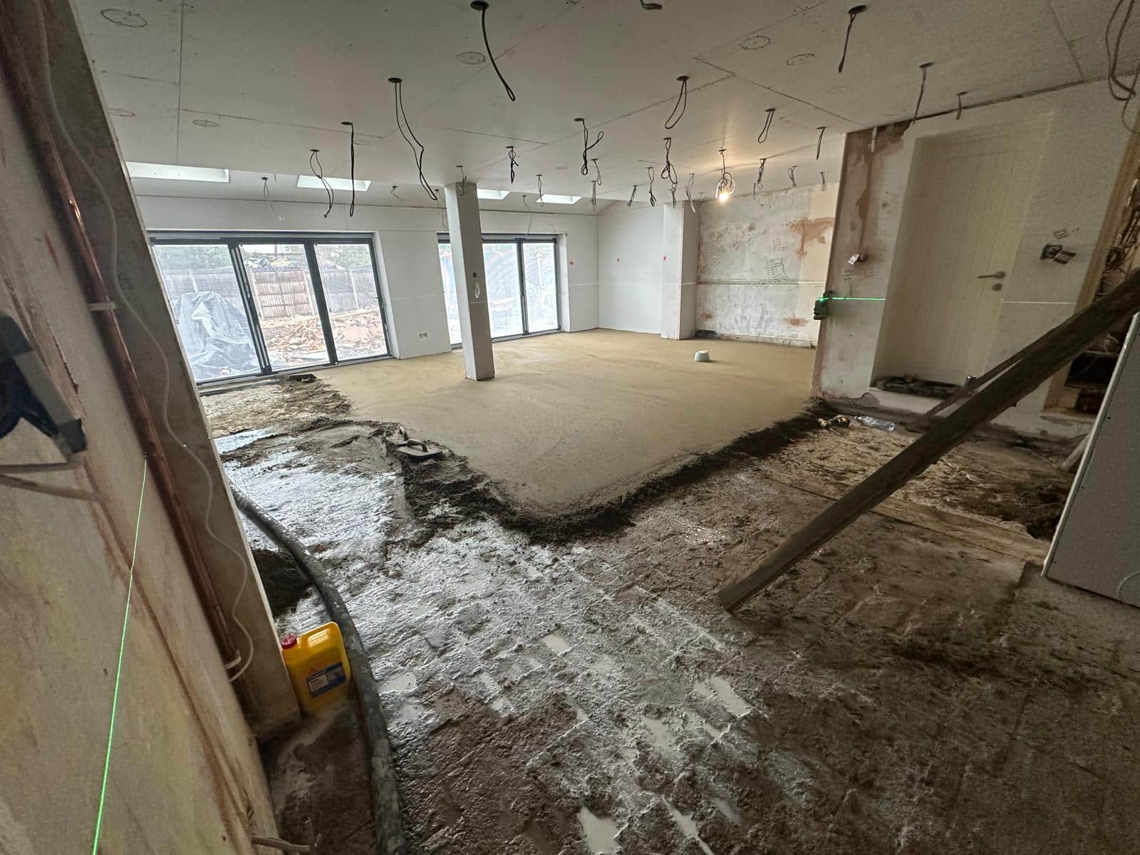 A room under construction with fresh floor screed being applied to the floor.