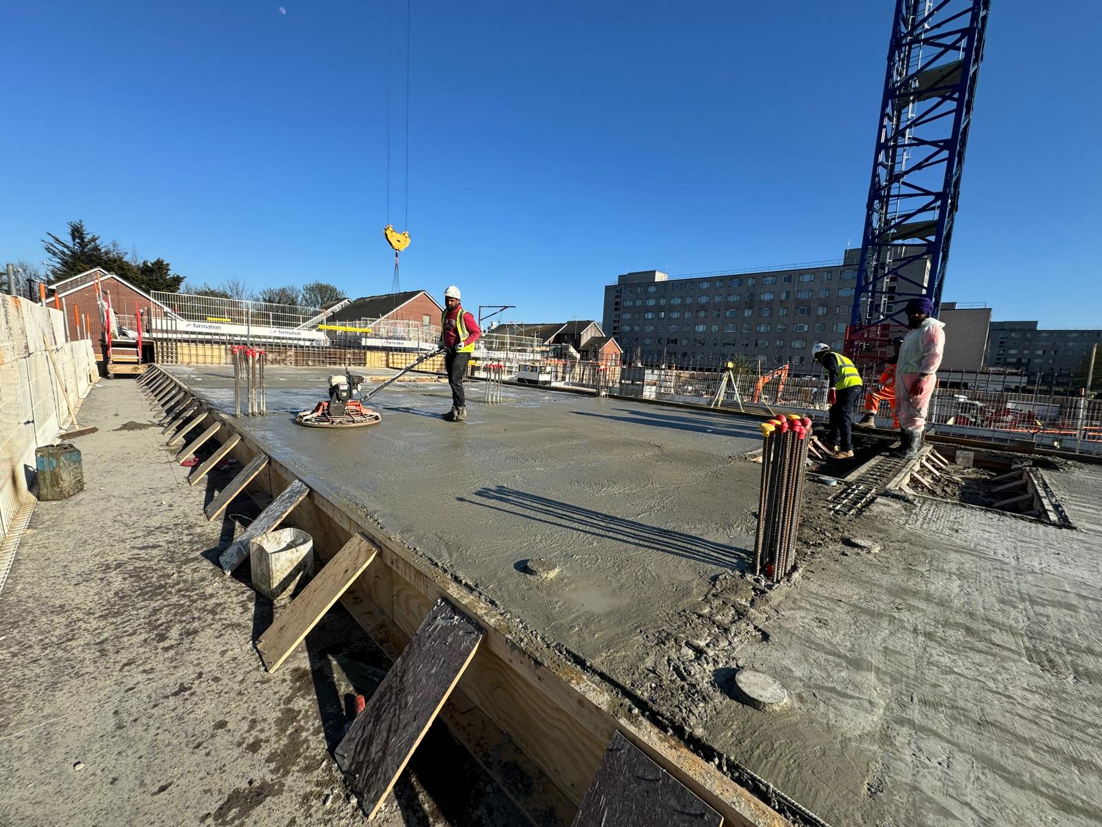 foundations6 Workers smoothing wet concrete on a building foundation at a construction site.