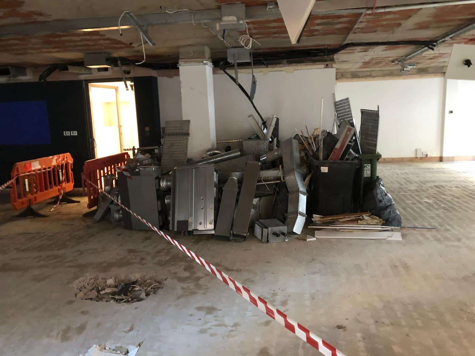 jerman street Piles of construction debris and metal pieces inside a partially renovated building.