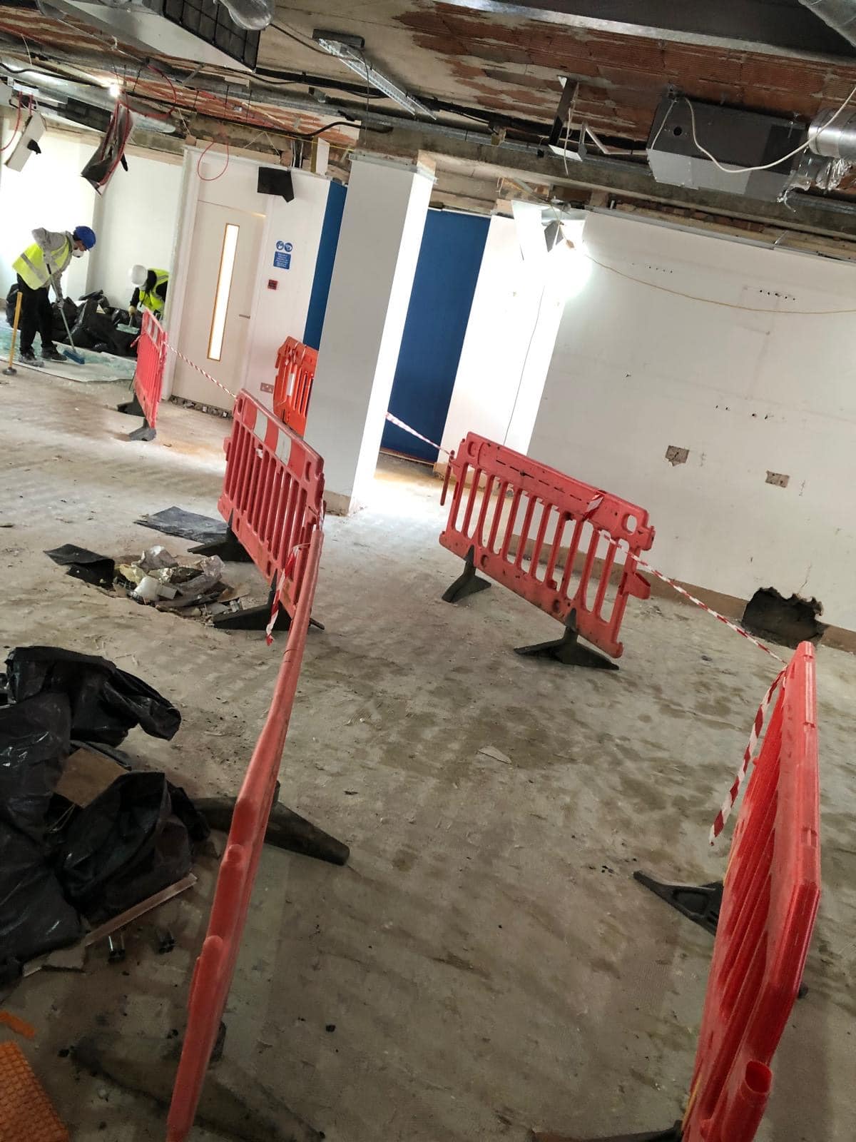 jermyn street2 Construction site with orange safety barriers and workers in a partially finished room.