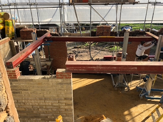 Partially built brick structure with steel beams at a construction site.