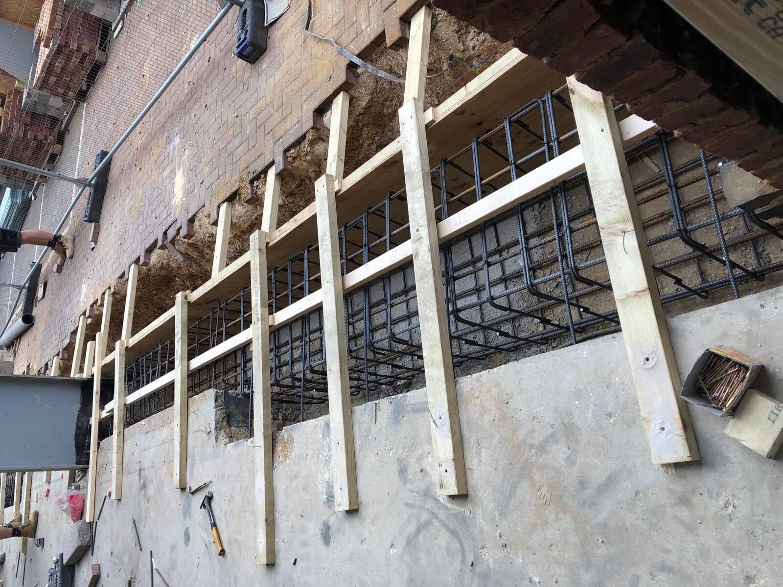 reading civils Wooden and steel framework for concrete construction against a brick wall.