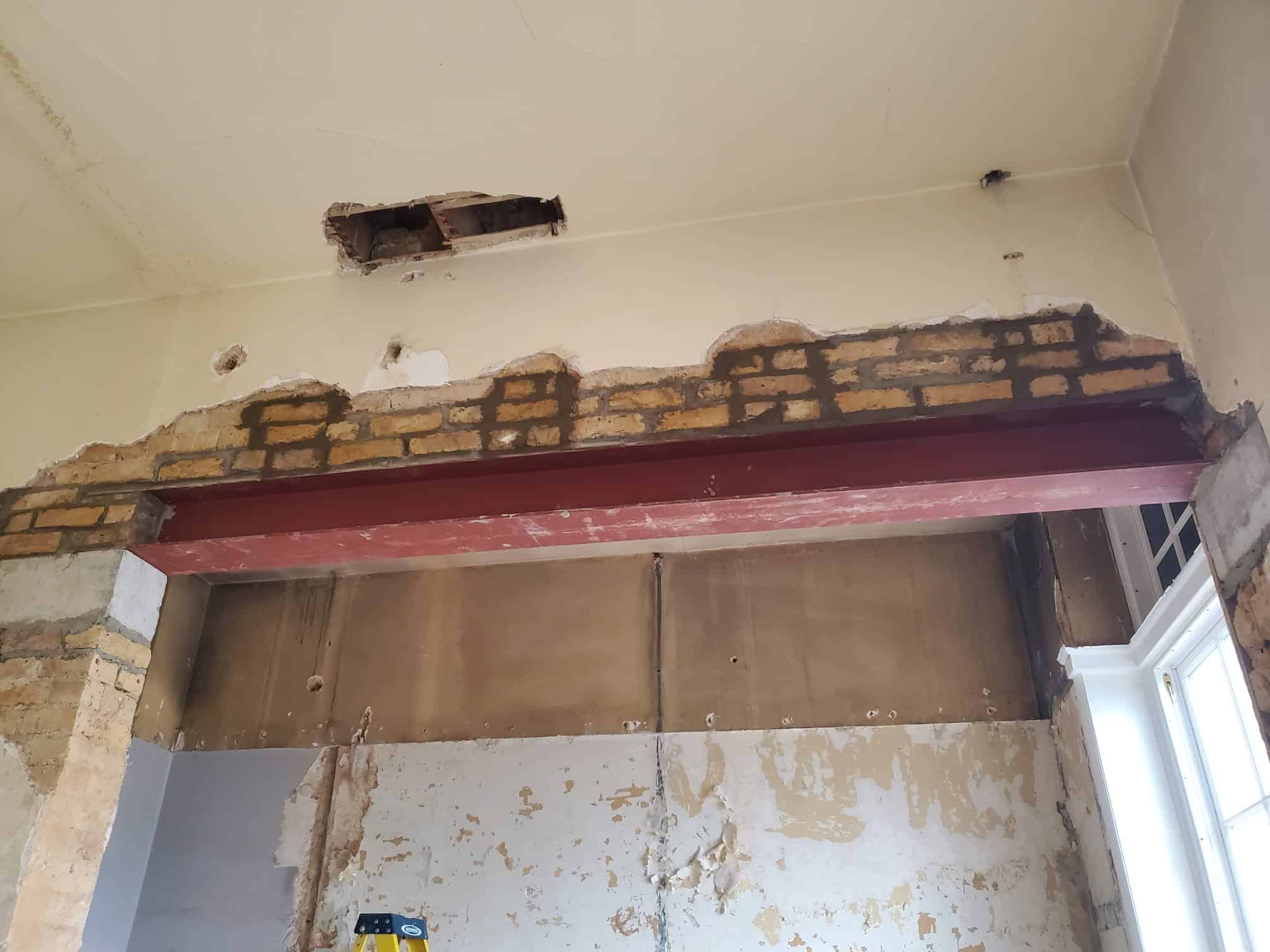 steels07 A steel beam is installed in a partially demolished brick wall inside a room.