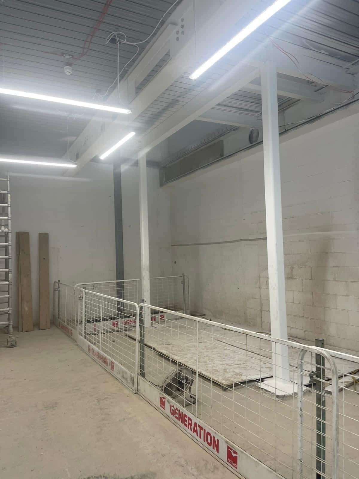 steelsfirestopping03 White steel beams in an indoor construction site, fenced off for safety.